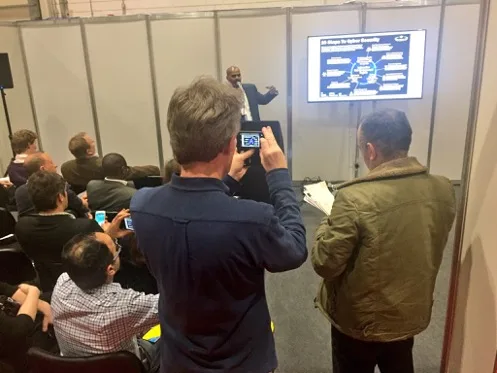 Michael Abtar presenting a cyber security slide to a seated audience in an exhibition seminar space.