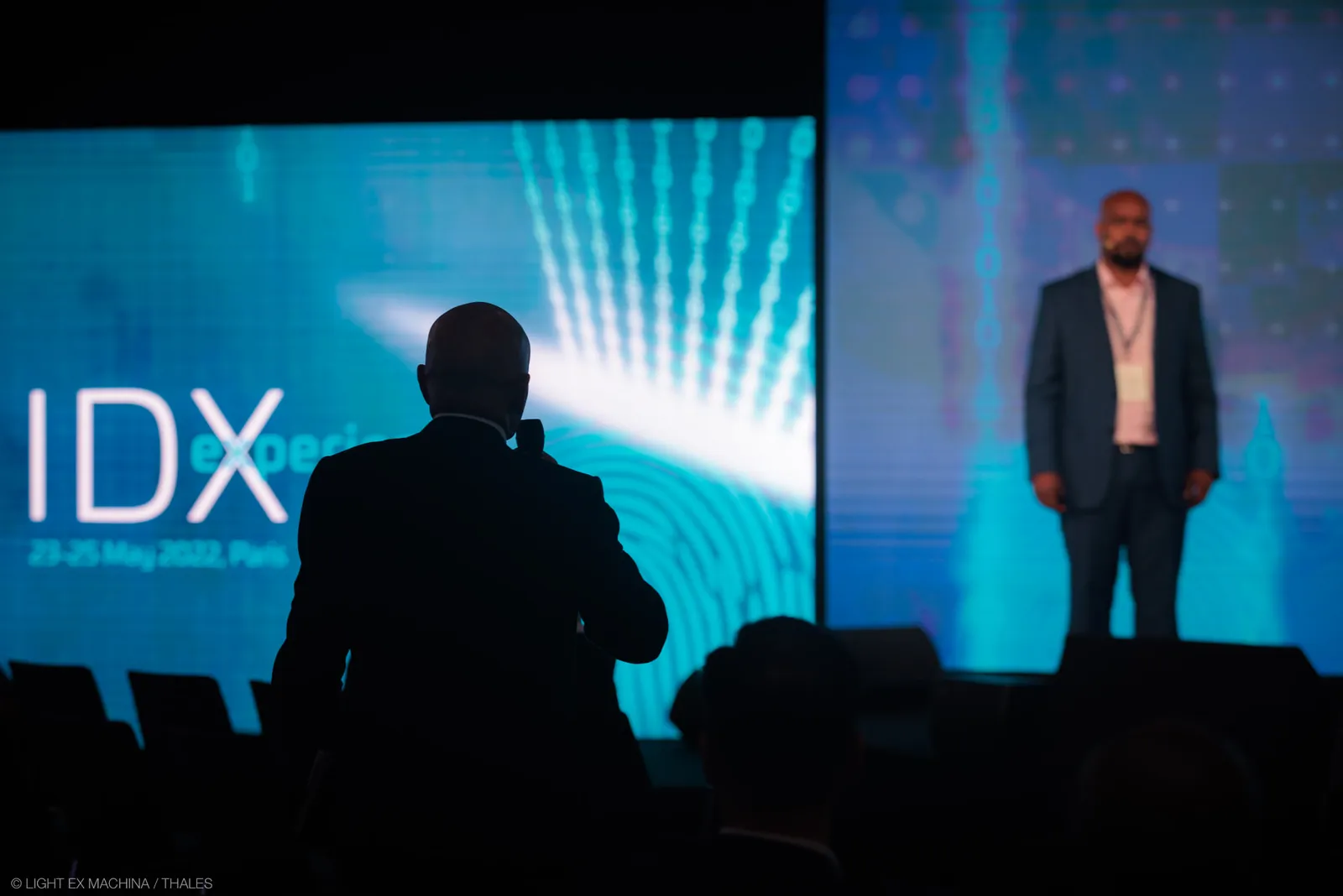 An audience member, in silhouette, asks a question while Michael Abtar listens on stage at the Thales IDX conference in Paris.