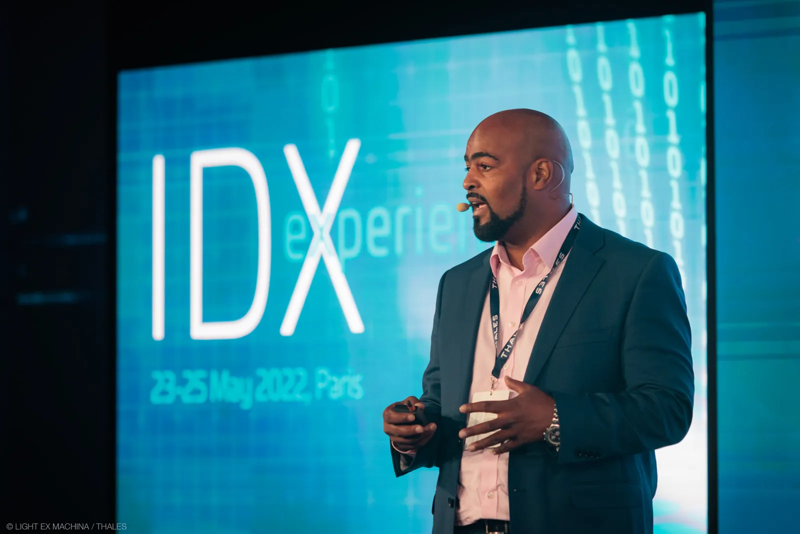 Michael Abtar speaking on stage with a headset microphone in front of an IDX conference screen reading 23–25 May 2022, Paris.