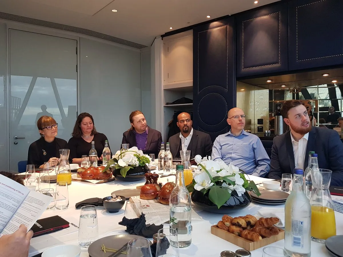 Michael Abtar seated at a round breakfast table with members of the Profusion team in a London meeting room.
